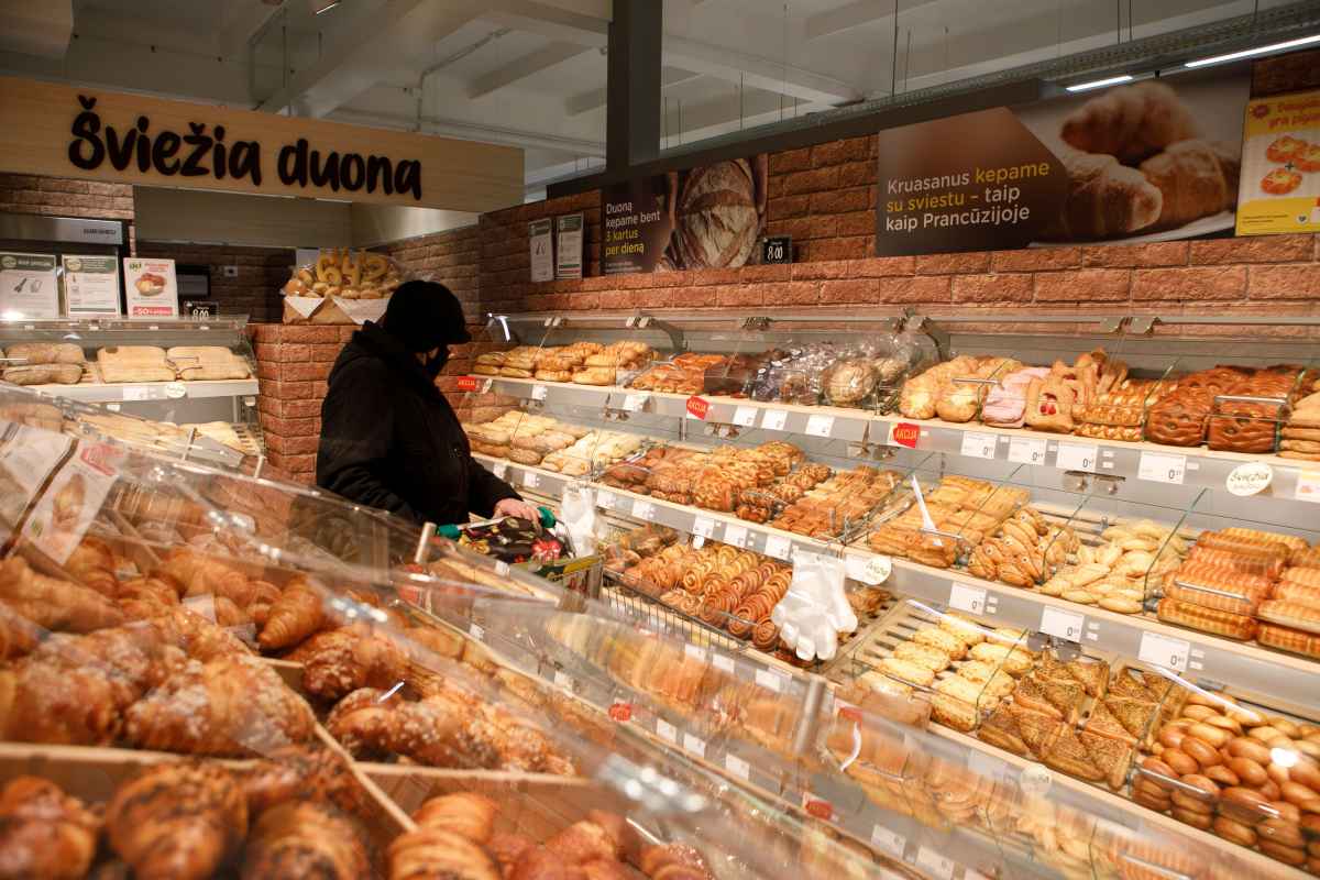 Žmogus apsirengęs juodai renkasi kepinius kepinių skyriuje.